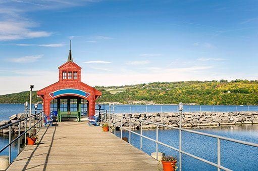 A wooden pier leading to a red building overlooking a body of water.