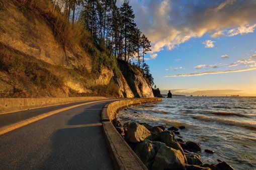 A road going down a hill next to a body of water.