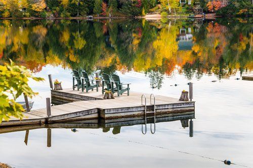 There is a dock with chairs on it in the middle of a lake.