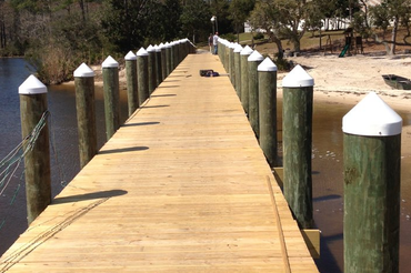 A long wooden dock with green poles and white caps