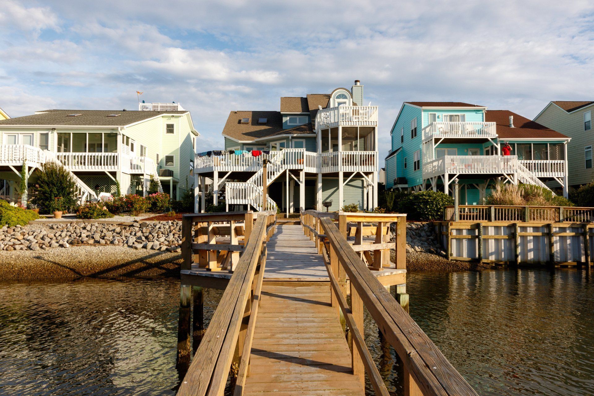 A wooden dock leads to a row of beach houses