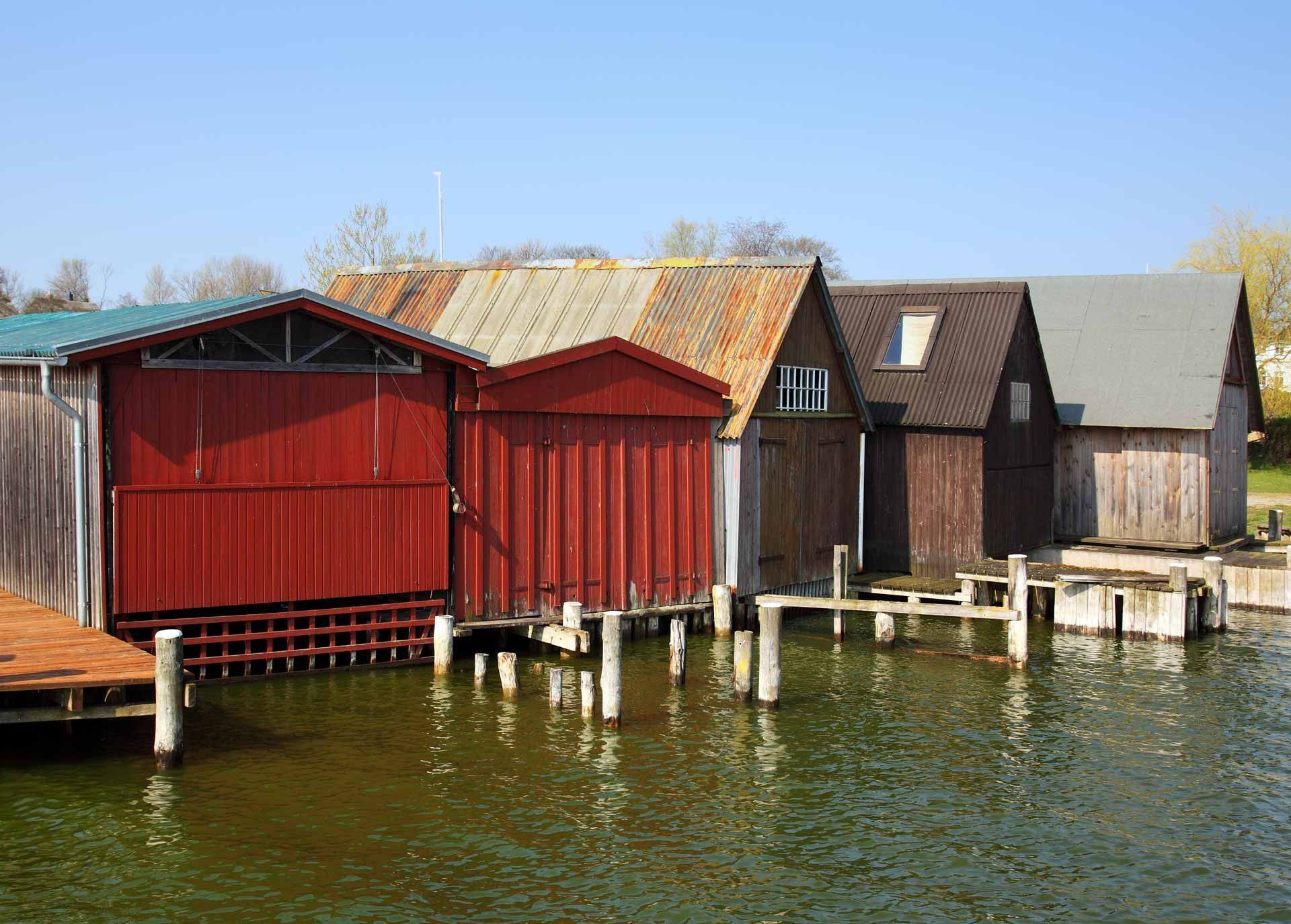 A row of wooden houses sitting on top of a body of water.