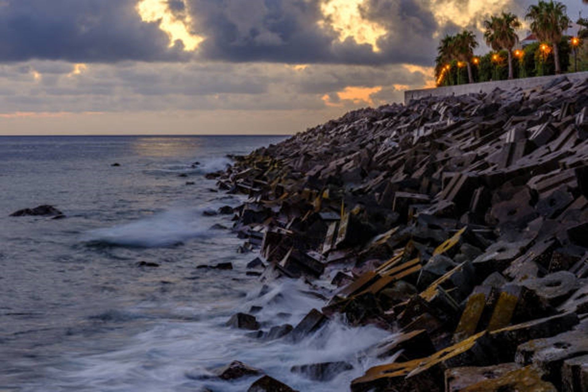 Waves crashing against a rocky shoreline at sunset