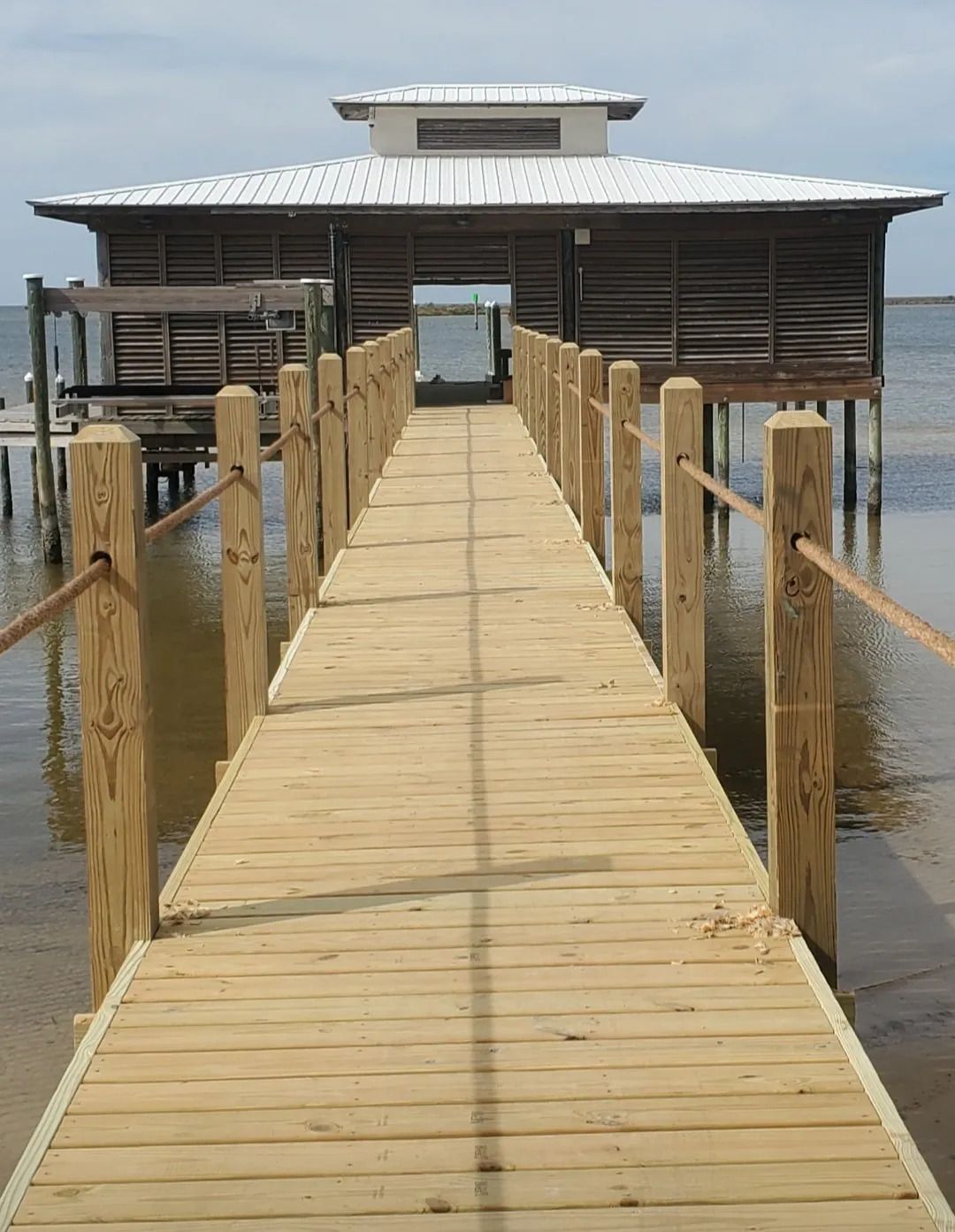 A long wooden dock leads to a house in the water