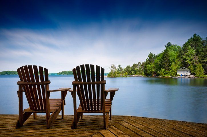 Two wooden chairs on a dock overlooking a lake