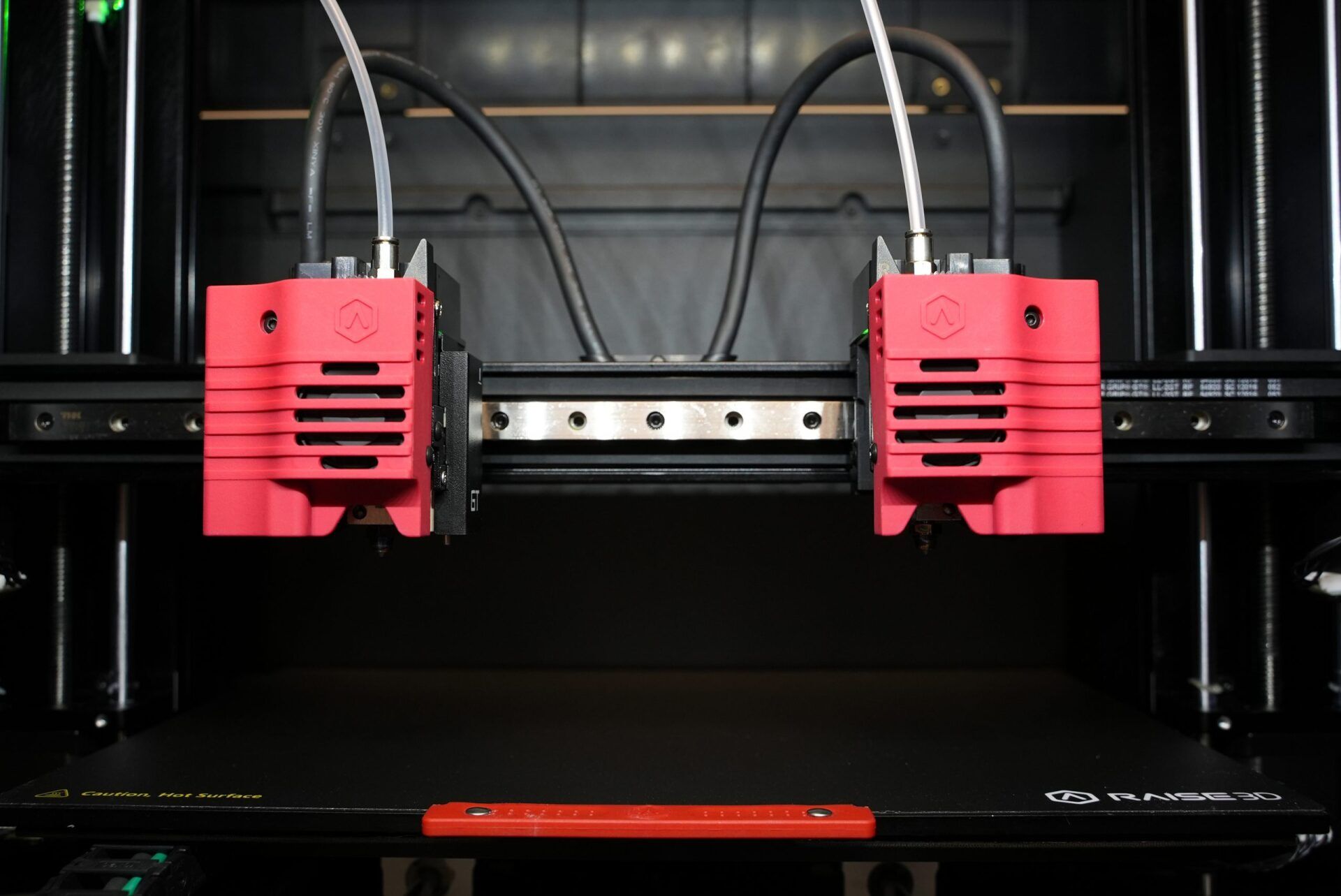 Een 3D-printer met twee rode koppen eraan verbonden