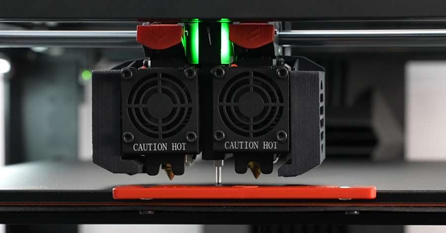 Een close-up van een 3D-printer die een rood voorwerp print.