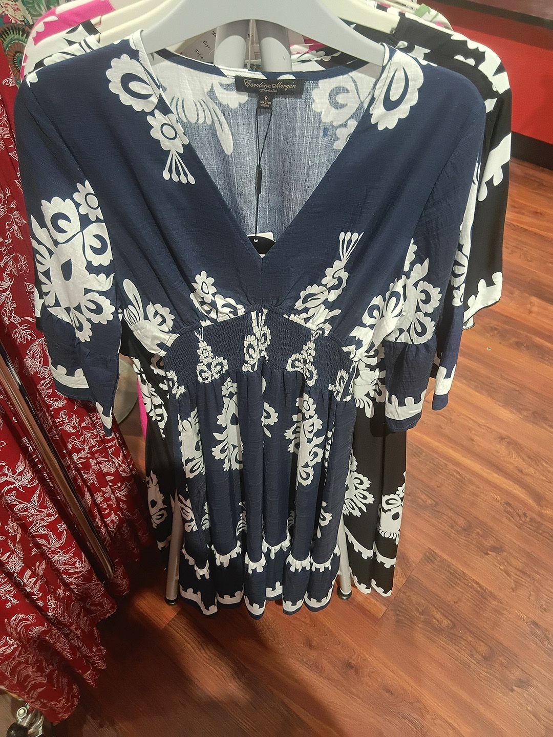 Clothing rack with dresses: light blue wrap dress, floral sundress, polka dot dress.