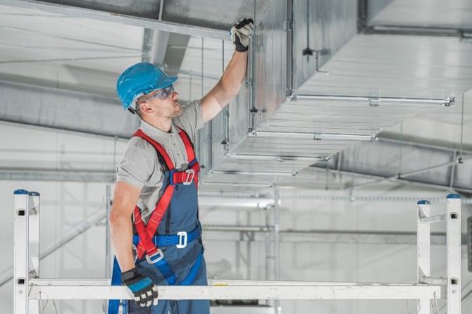 A man is standing on a ladder working on a ceiling.