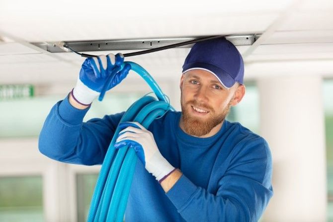 A man is working on a ceiling with a hose.