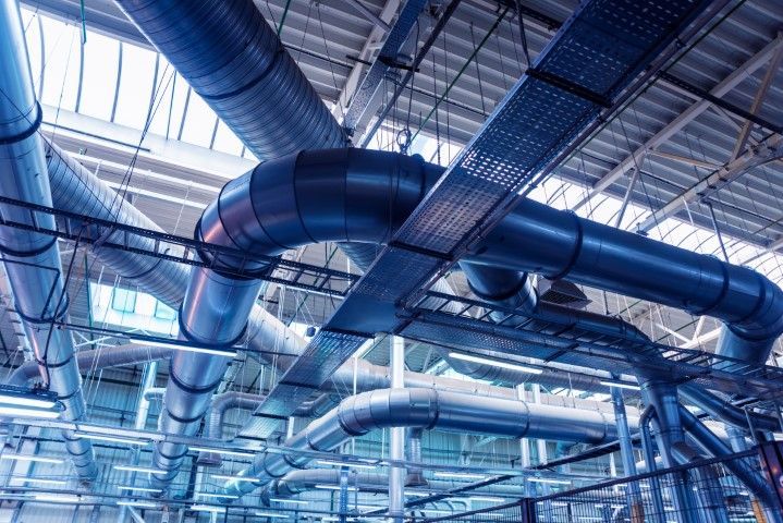 A factory with a lot of pipes hanging from the ceiling.