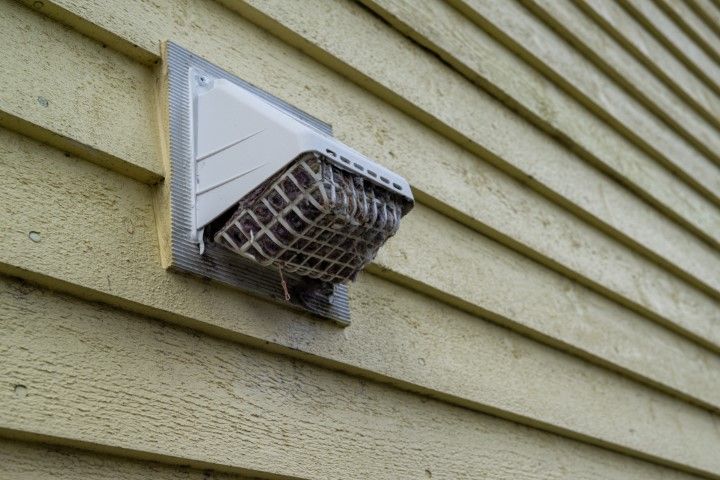 A close up of a vent on the side of a house.