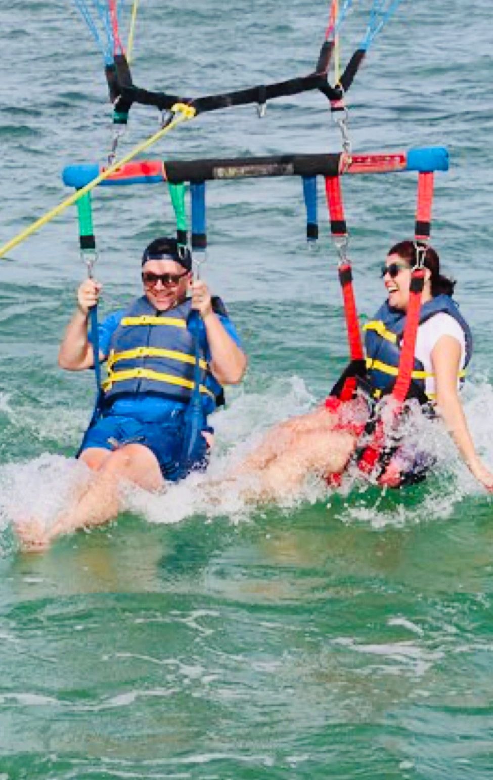 A man and a woman are parasailing in the ocean.