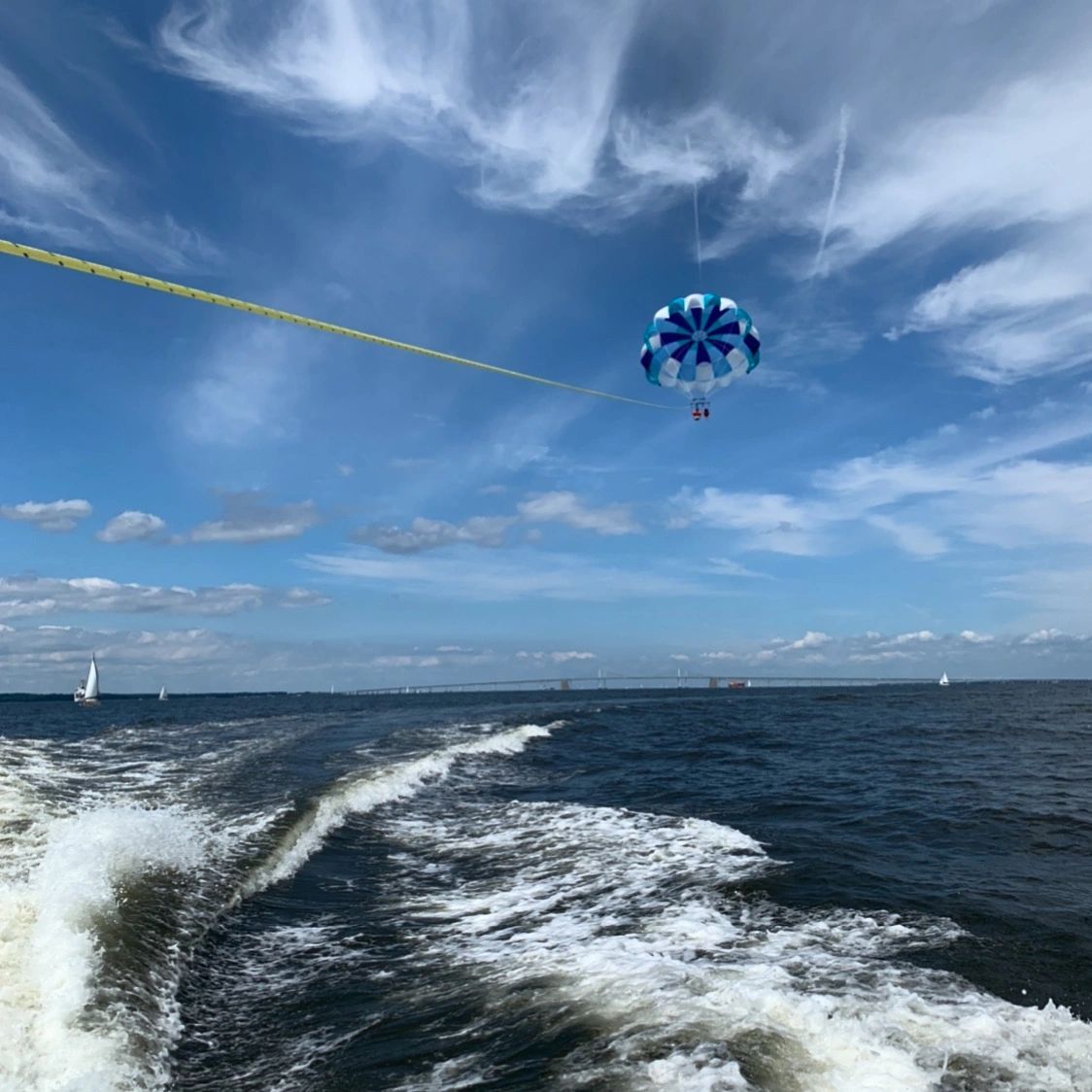 A person is parasailing over a body of water.