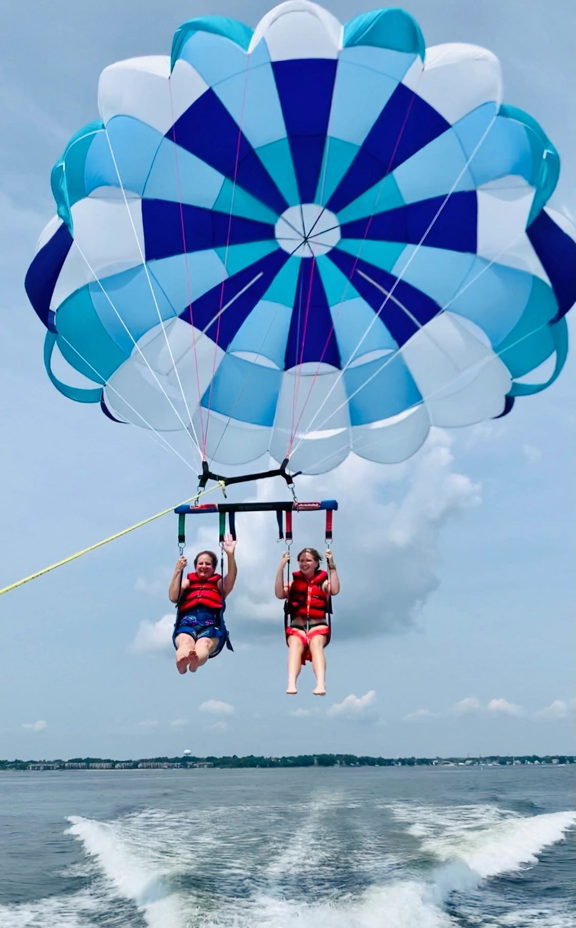 Two people are parasailing over a body of water.