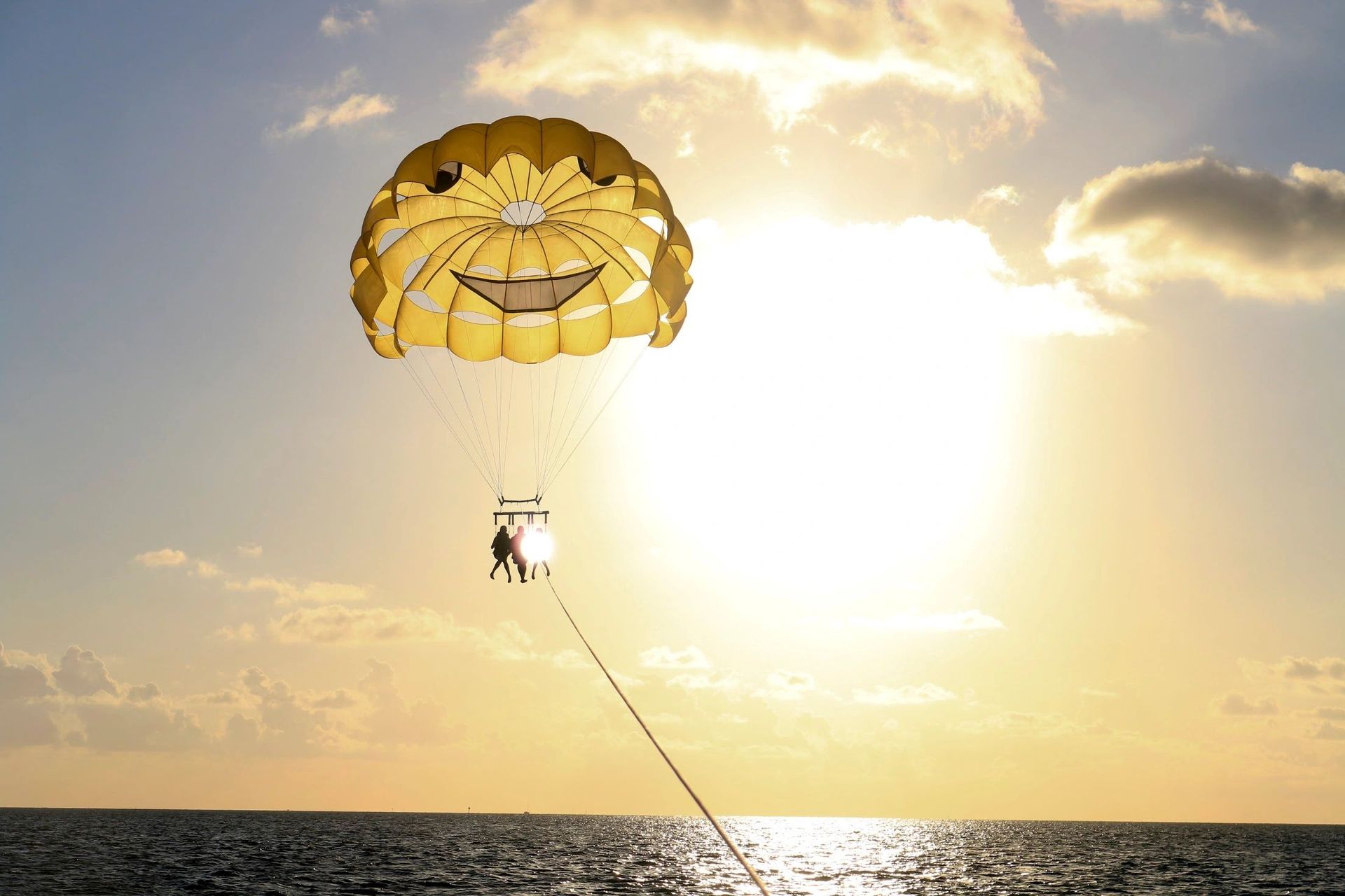 A person is parasailing over the ocean at sunset
