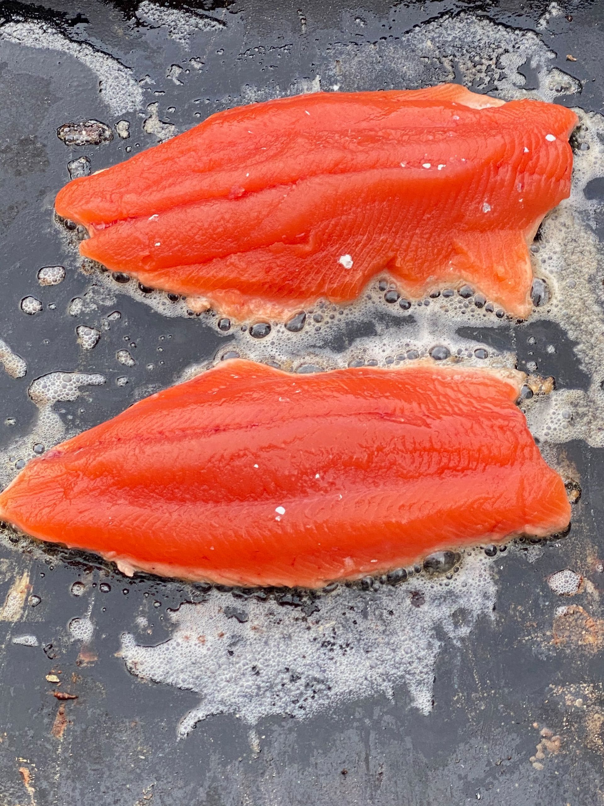 Chef in white coat and striped apron prepares vegetables in a kitchen overlooking the sea.
