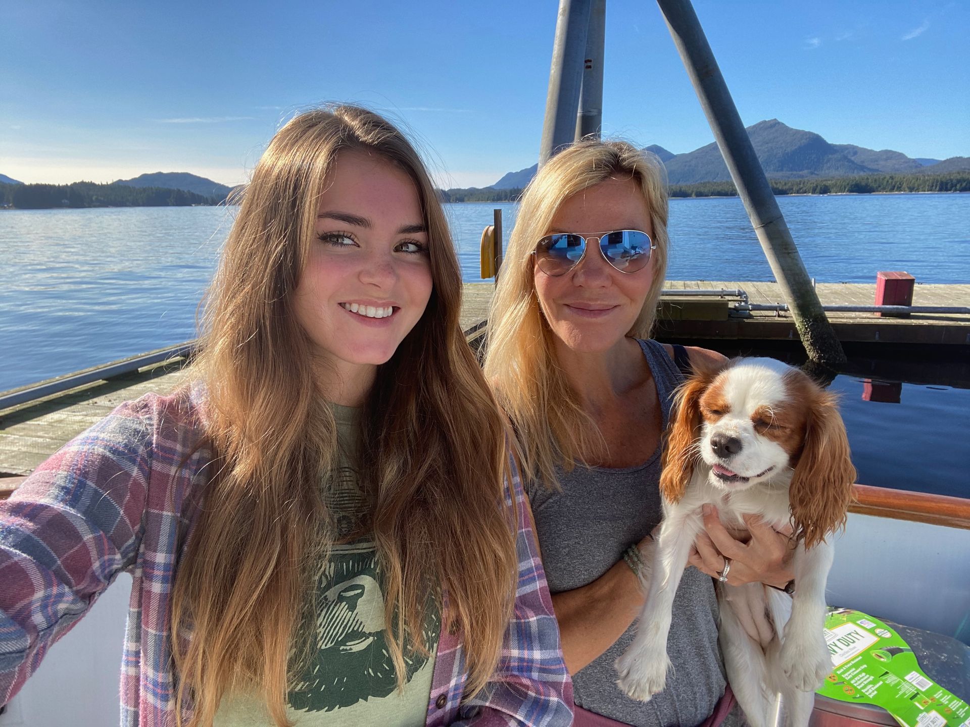 Three people hiking on a forest trail toward sunlight and mountain peaks.