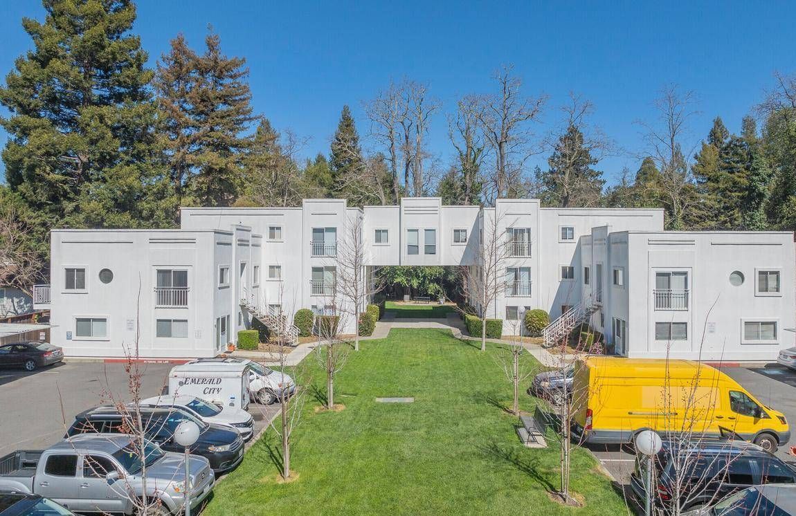 Photo showing an apartment community with the parking lot in the foreground