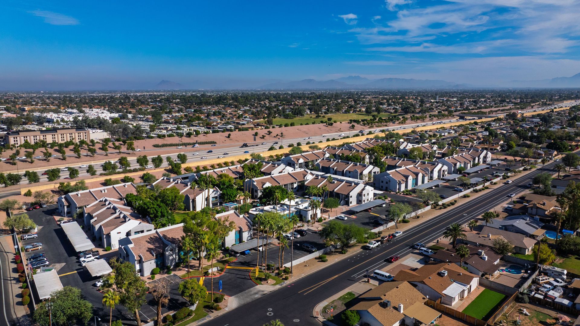 Aerial view of residential buildings and roads under a clear blue sky.