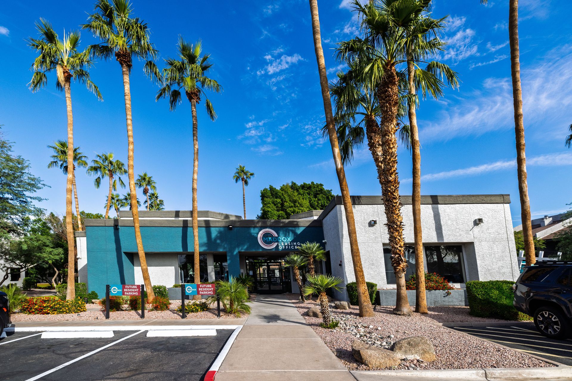 Building with teal and white walls, palm trees, blue sky.