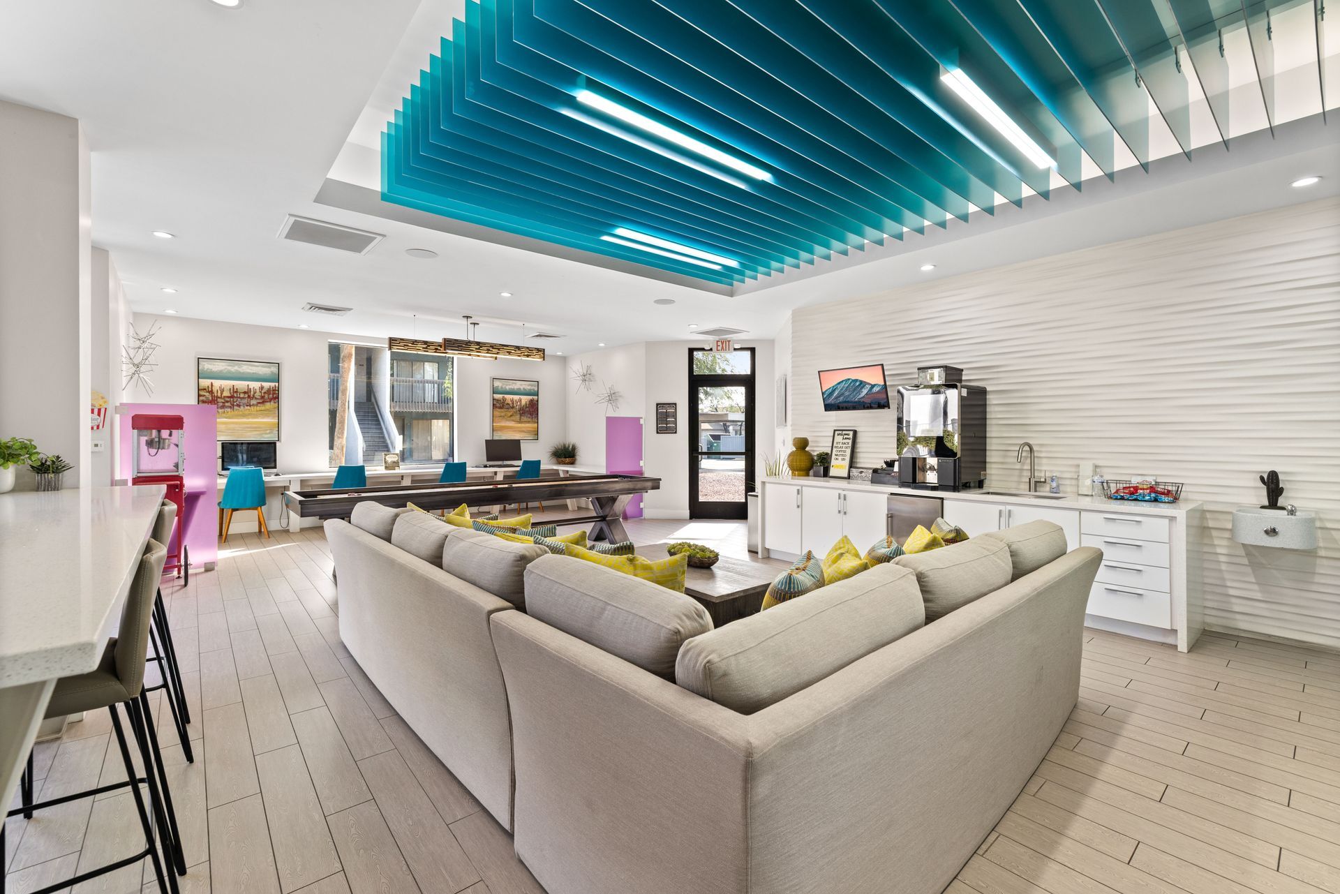 Modern lounge with a large gray sectional sofa, white and blue ceiling, and white walls.