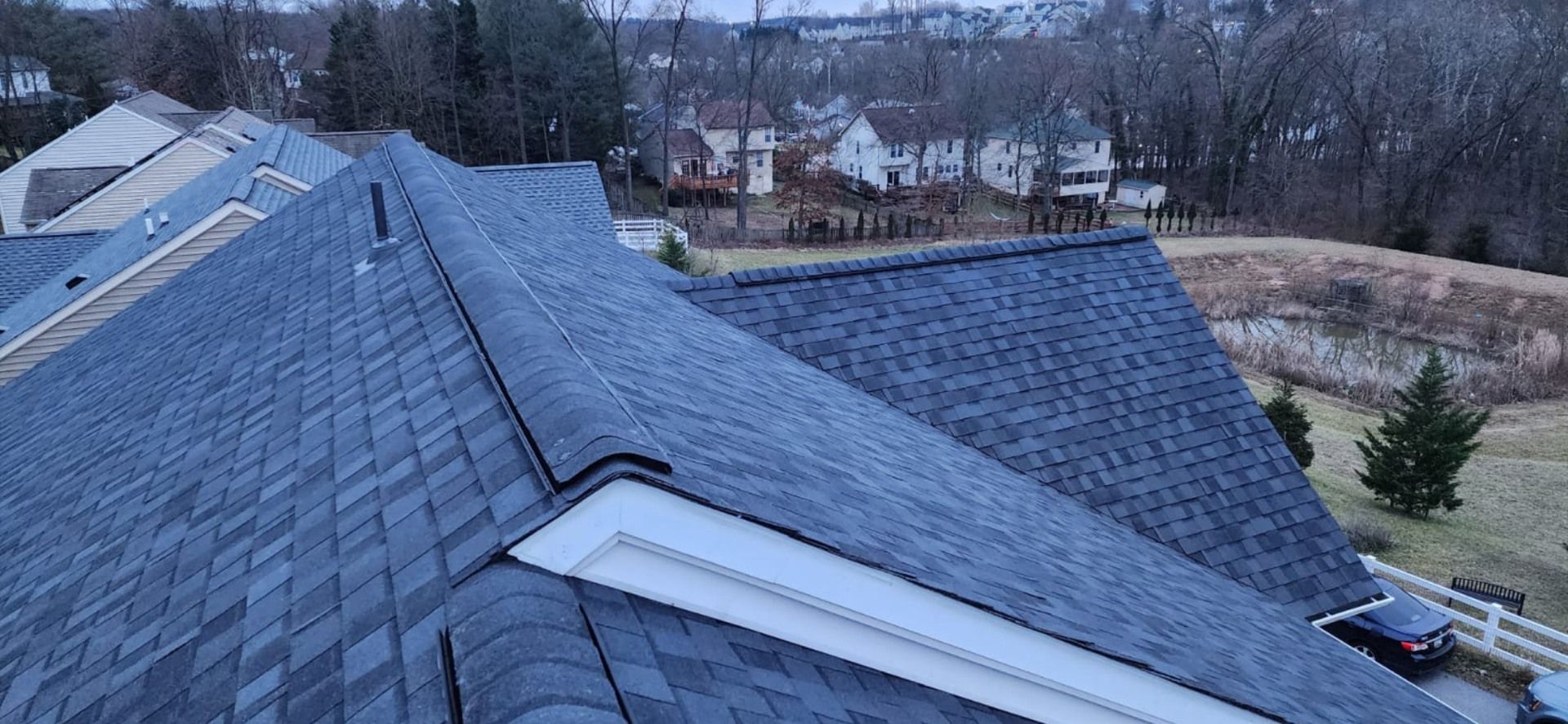 An aerial view of a roof of a house with a car parked in front of it.