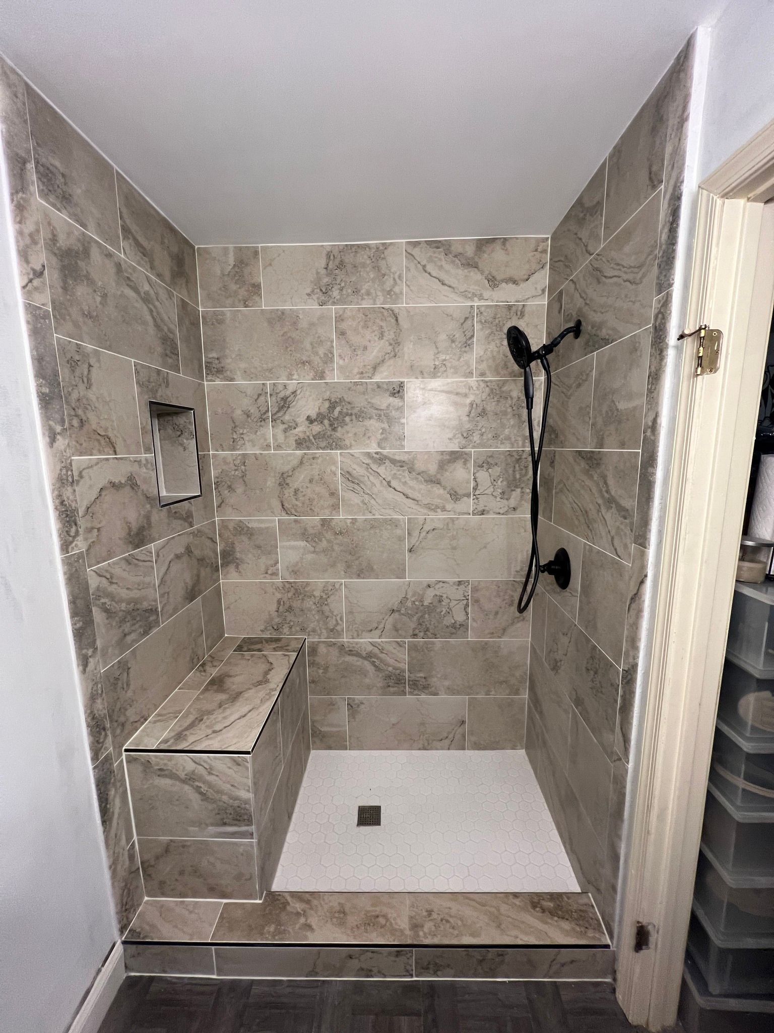 A bathroom with a walk in shower and a bench.