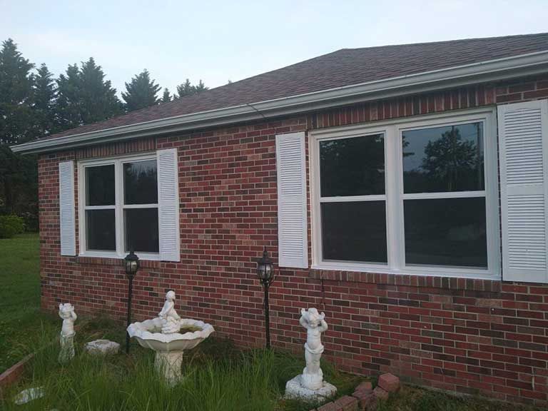 A brick house with white shutters and a fountain in front of it.