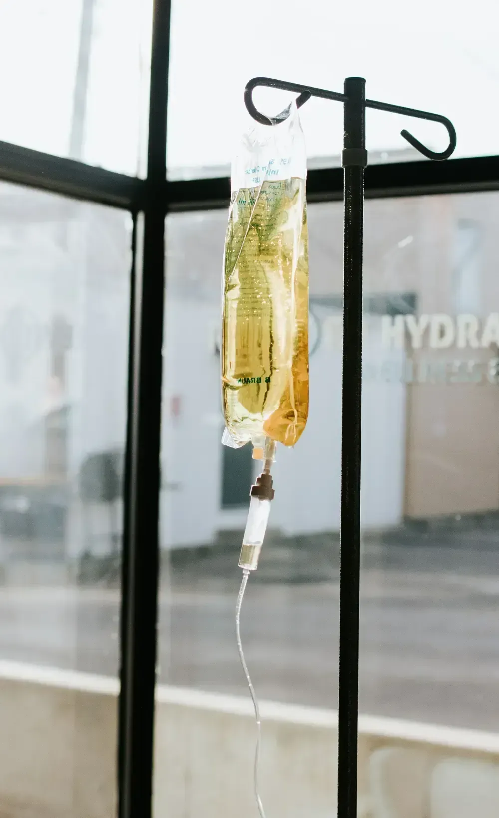 Hangover iv -  drip filled with a golden solution, hanging from an IV stand in a wellness center, used for rapid hydration and hangover recovery.