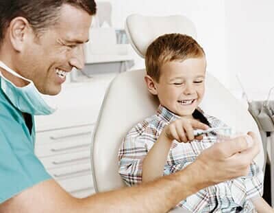 Dentist Showing a Young Boy How to Brush His Teeth — Orthodontics in Owosso, MI