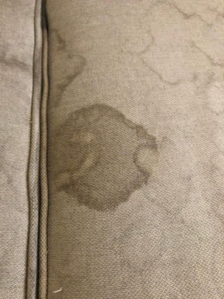 A close up of a couch with a stain on it.