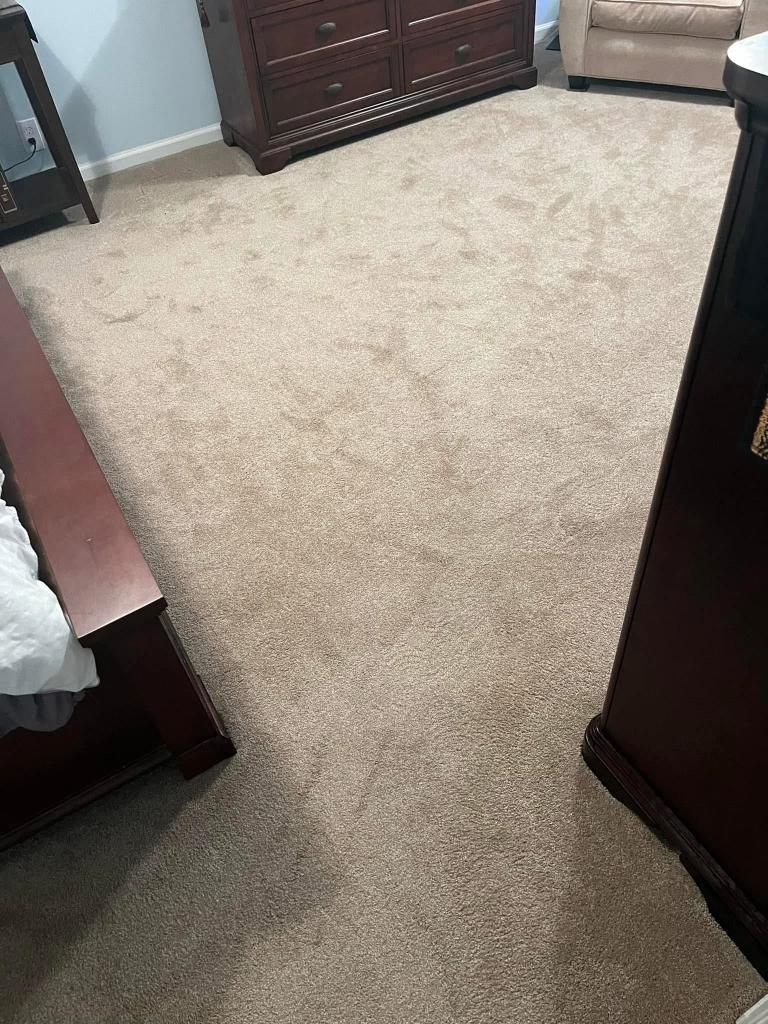 A living room with a large carpeted floor and a dresser.