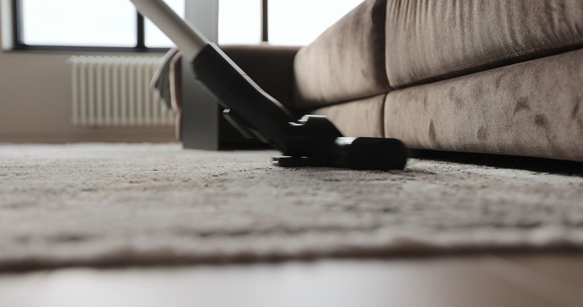 A person is using a vacuum cleaner to clean a carpet in a living room.