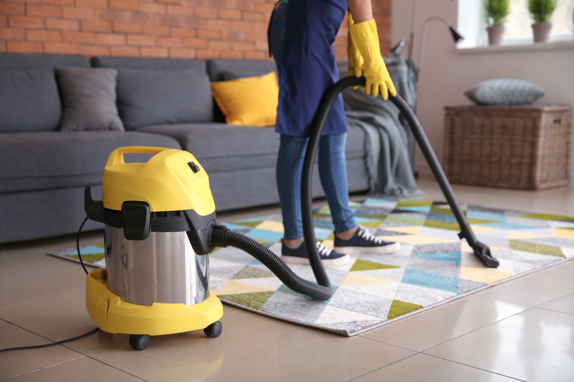 A woman is using a vacuum cleaner to clean a rug in a living room.