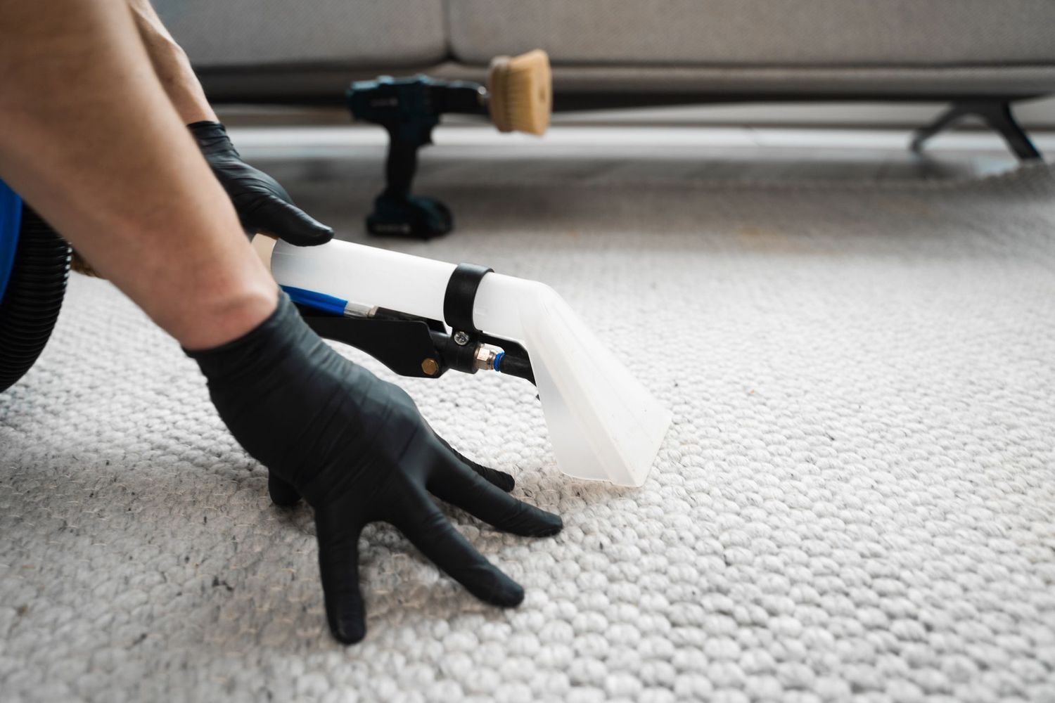 A person is cleaning a carpet with a vacuum cleaner.