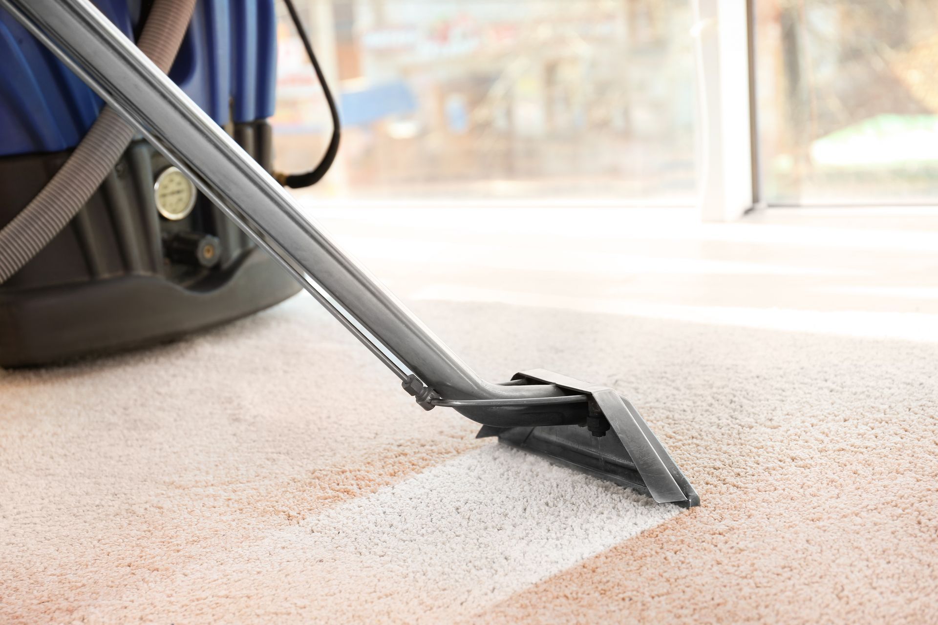 A vacuum cleaner is cleaning a carpet in a room.