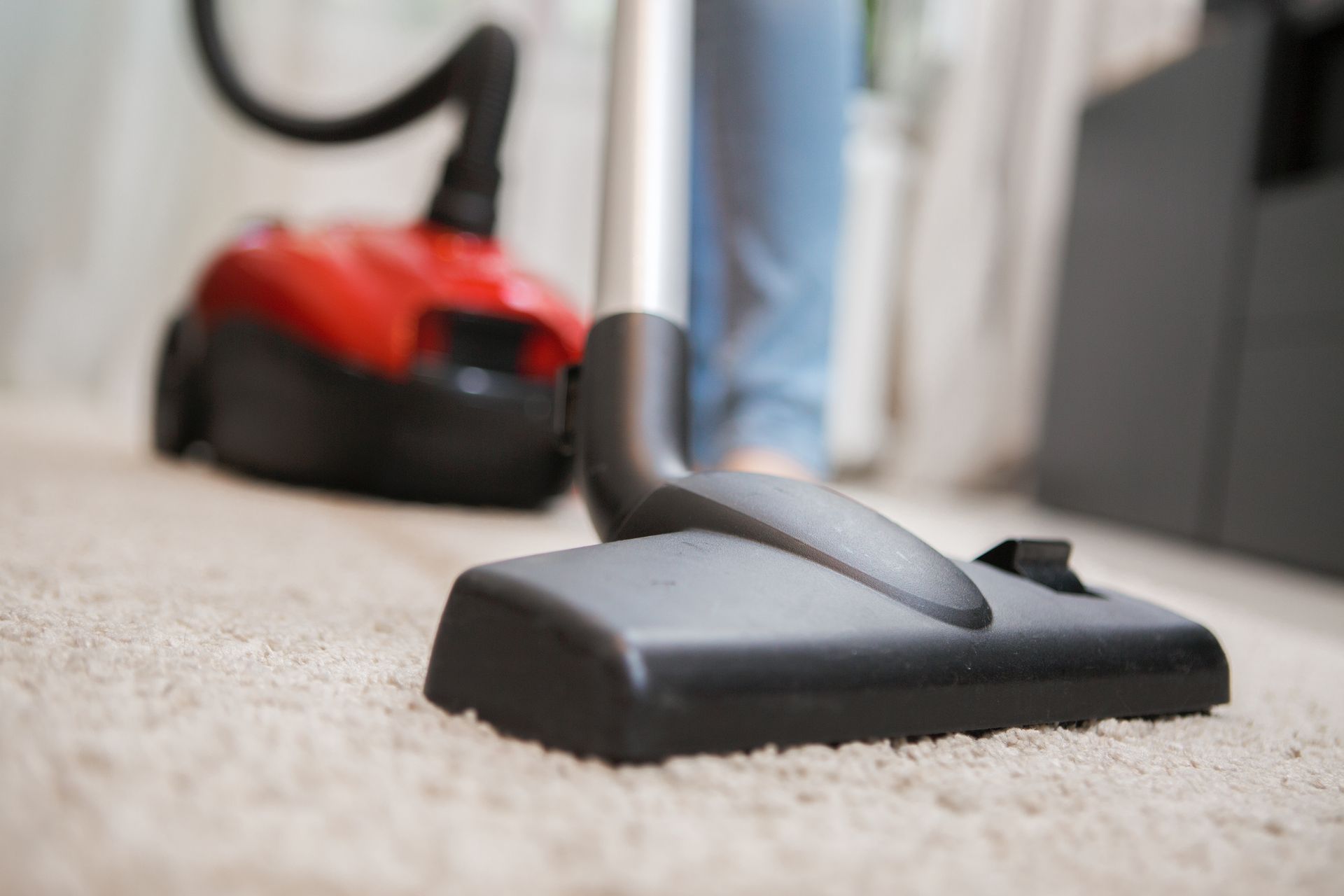 A person is using a vacuum cleaner to clean a carpet.