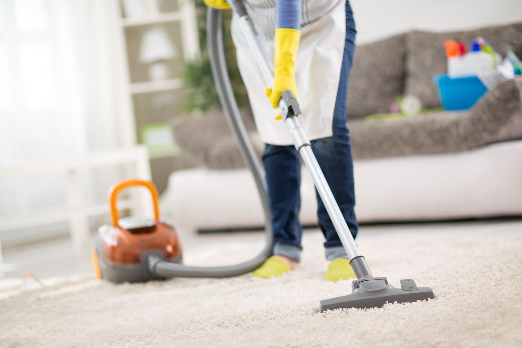 A woman is using a vacuum cleaner to clean a carpet in a living room.