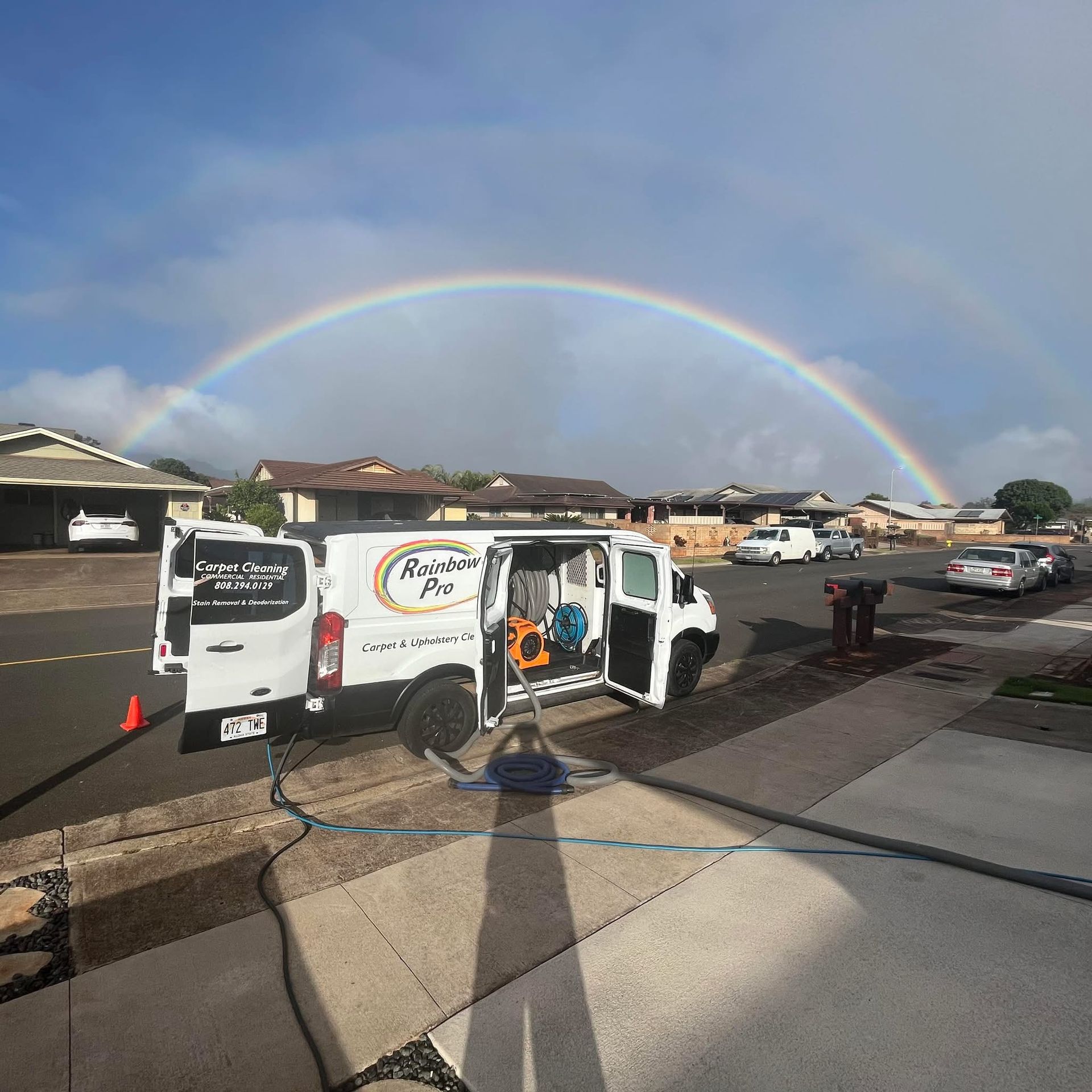 A white van is parked in front of a rainbow