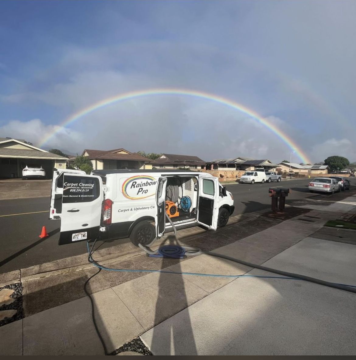 A white van is parked in front of a rainbow