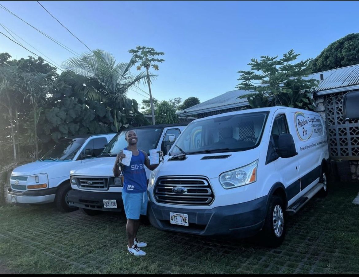 A man is standing in front of three white vans.