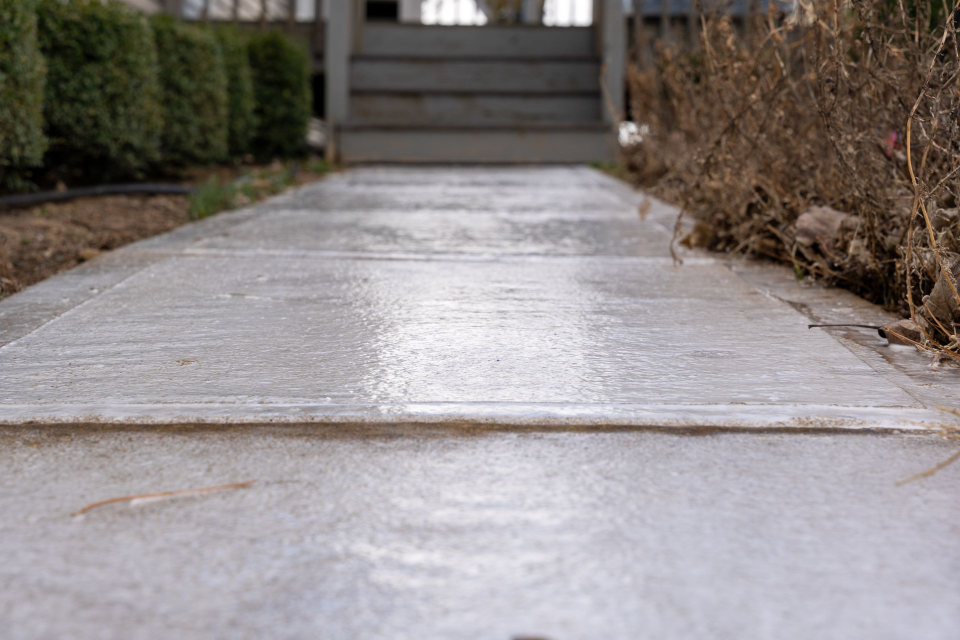 A concrete walkway leading to a house with stairs.