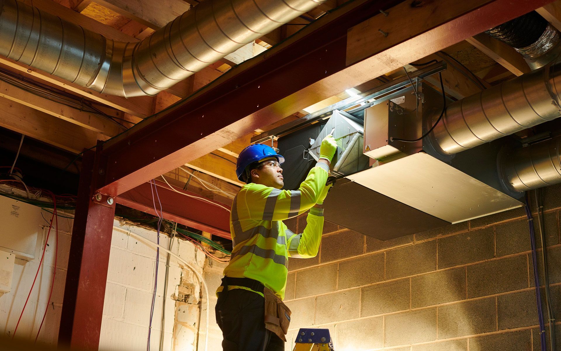 A man is working on a ventilation system in a building.