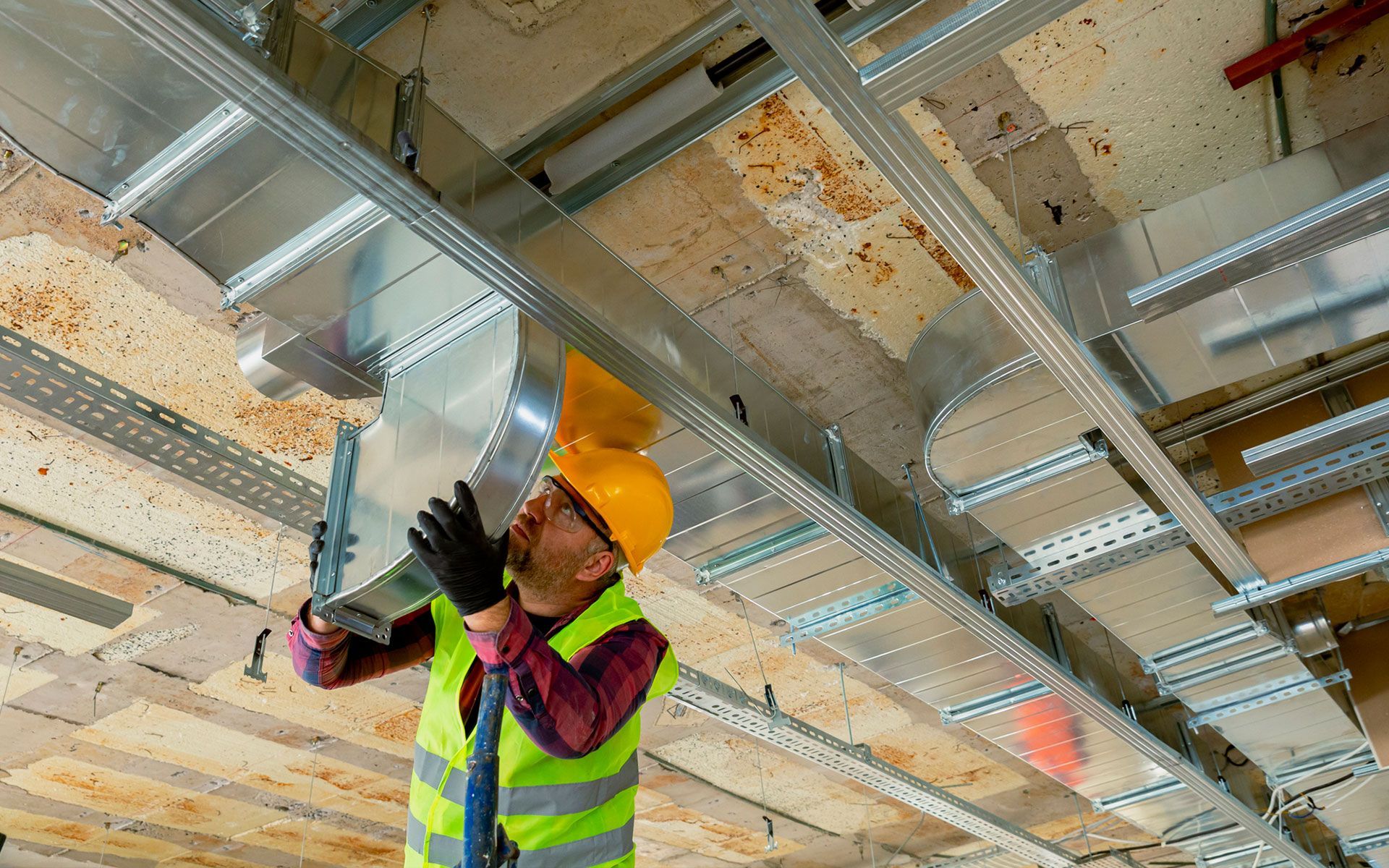 A construction worker is working on the ceiling of a building.