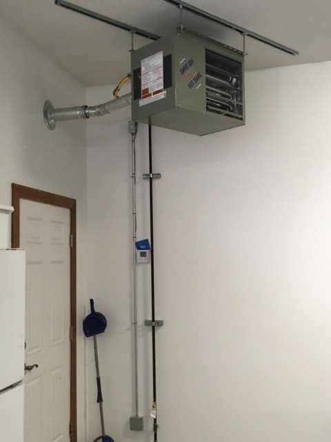 A room with a heater hanging from the ceiling