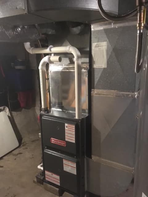 An air conditioner is sitting in the corner of a room in a basement.