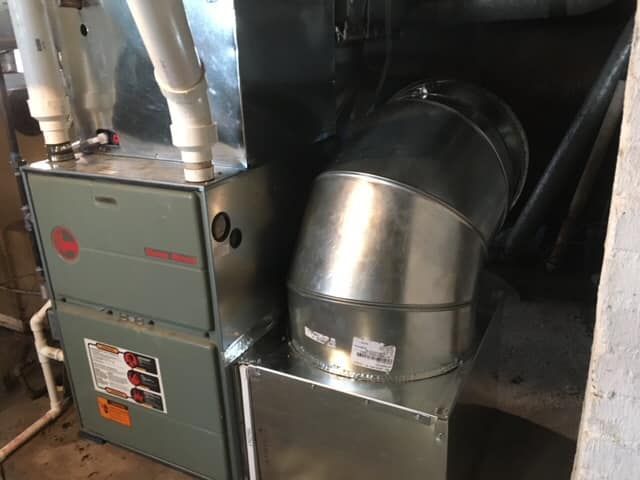 A furnace and air conditioner are sitting next to each other in a room.