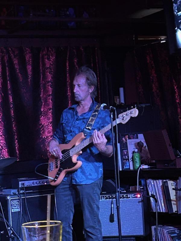 Matt Feinberg in a blue shirt is playing a guitar on stage