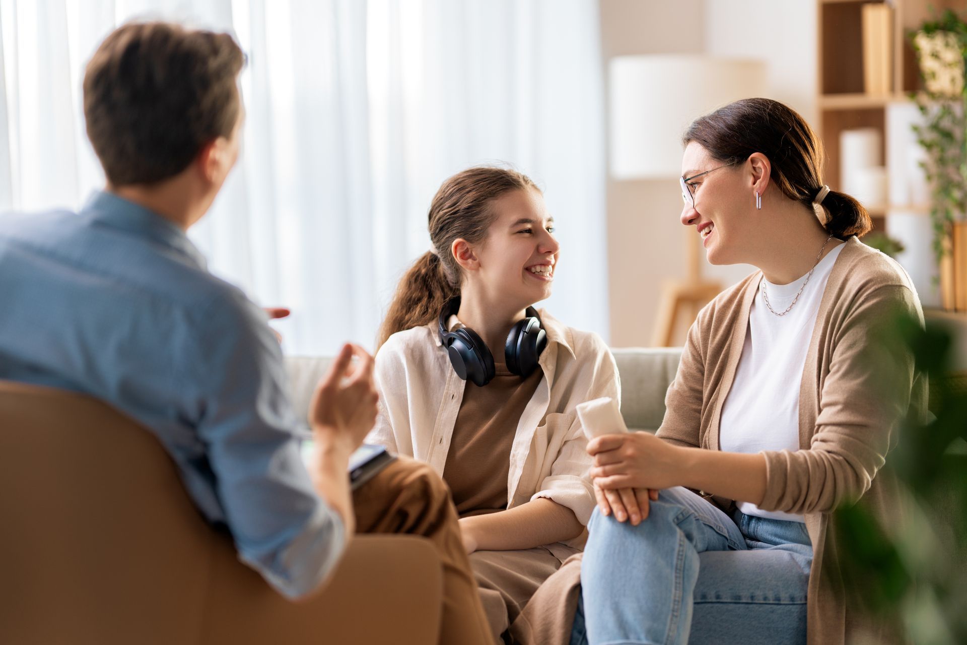 Family smiling and talking on a couch in a well-lit living room.